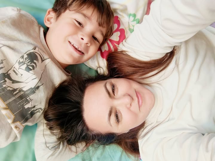 אישה וילד קטן שוכבים על מיטה, מחייכים למצלמה כשהם לבושים בחולצות בהירות. - דפנה פורמן, הרצאות, ייעוץ וטיפול רגשי במעברים וברילוקיישןש